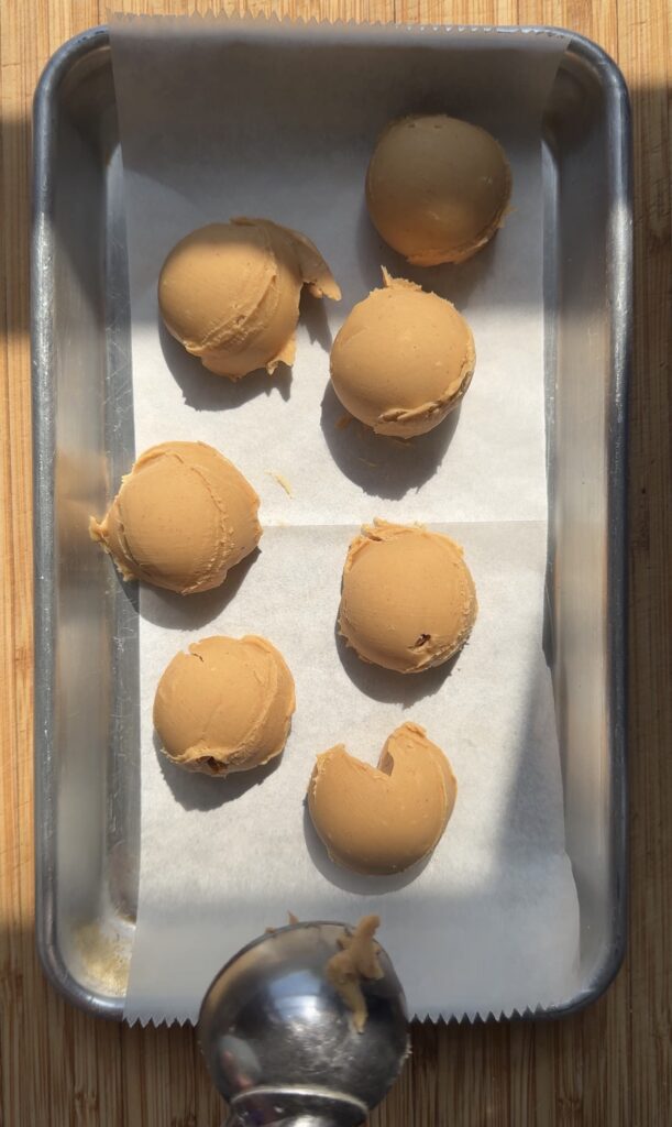 A purple portion scoop scooping up peanut butter filling for buckeye cookies