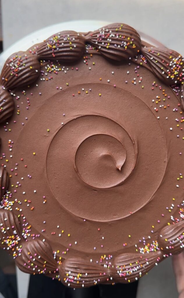 A top-down view of a buttercream swirl on a chocolate birthday cake