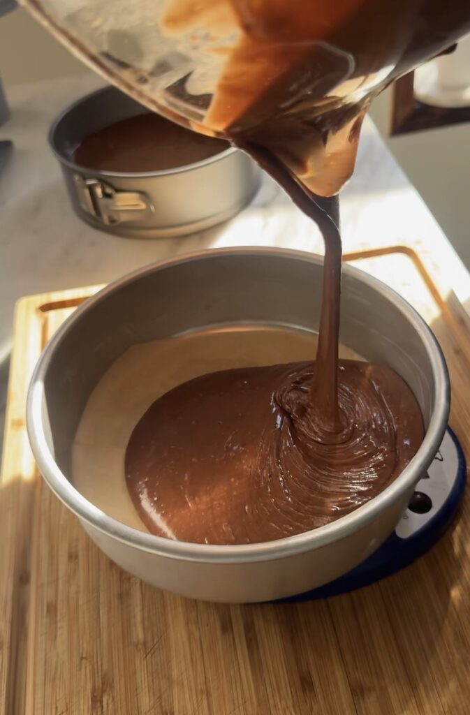 Chocolate birthday cake batter is poured into a cake pan